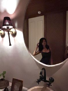 a woman taking a selfie in front of a bathroom mirror with her hair dryer