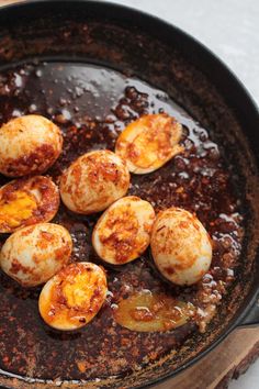 cooked eggs are in a skillet with brown sauce and seasoning on the side