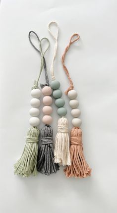 three tasseled beads and one beaded necklace on a white background with the string attached