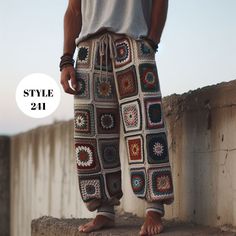 a man standing on top of a cement wall wearing crocheted pants and sandals