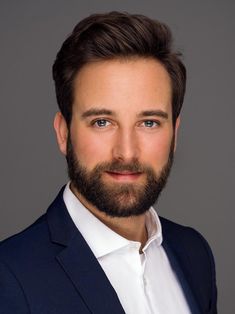 a close up of a person wearing a suit and tie with a goatee beard