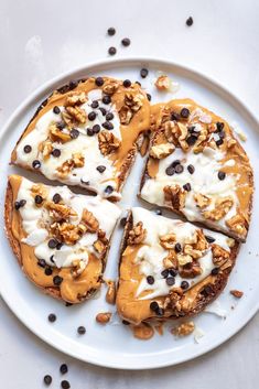 a white plate topped with slices of pizza covered in nuts and chocolate chips on top of a table