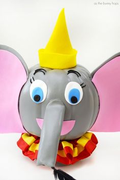 an elephant with a yellow hat on its head and some feathers around it's neck