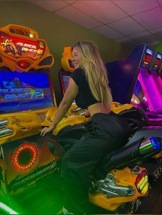 a woman sitting on the back of a motorcycle in front of some arcade game machines