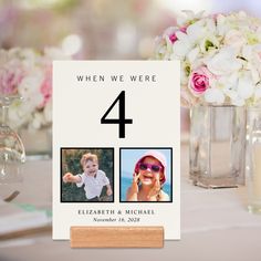 a table number with two photos on it and flowers in vases next to it