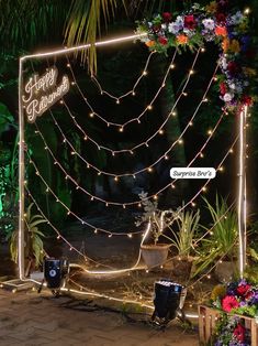 the entrance to a tropical garden decorated with flowers and lights for an outdoor wedding ceremony