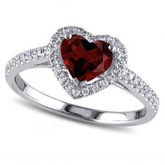 a heart shaped ring with diamonds around the band and a red stone in the center