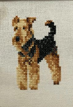 a cross stitch picture of a dog with a black vest on it's back