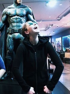 two people standing in front of a batman statue with their mouths open and eyes closed