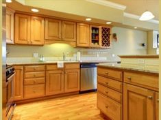 an empty kitchen with wooden cabinets and stainless steel dishwasher in the center island