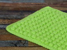 a green crocheted dishcloth sitting on top of a wooden table