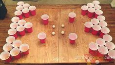 a wooden table topped with red cups filled with water and white plastic cups sitting on top of each other