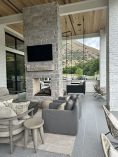 an outdoor living area with couches, chairs and a television mounted to the wall