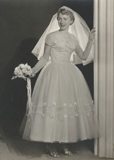 an old black and white photo of a woman in a wedding dress holding a bouquet