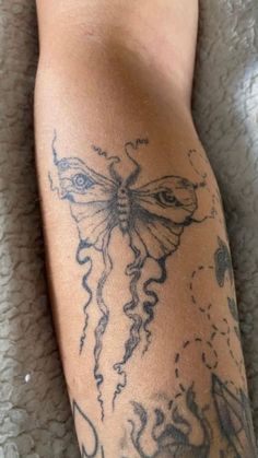 a close up of a person's leg with tattoos on it and a butterfly