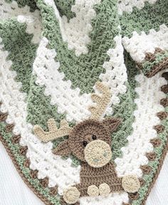 a crocheted blanket with a stuffed animal on it's side and a green, white, and brown afghan in the background