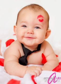 a baby wearing a black tie with red hearts painted on it