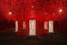 an art installation with red and black paint on the walls, in front of three doors