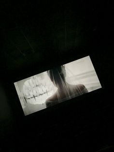 a woman standing in the dark with her face obscured by an image on a screen