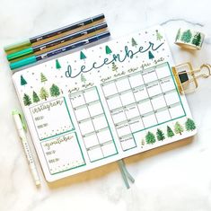 a planner with christmas trees on it next to some pens and pencils in front of them