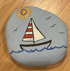 a painted rock with a sailboat on it