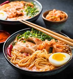 two bowls of ramen with chopsticks and an egg in the middle, on a table