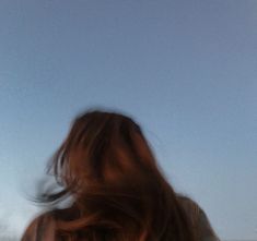 a blurry image of a woman flying a kite in the sky with her hair blowing