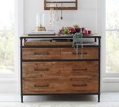 a dresser with two drawers and a mirror above it in a white room next to a window