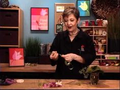 a woman standing in front of a wooden table with scissors and flowers on top of it