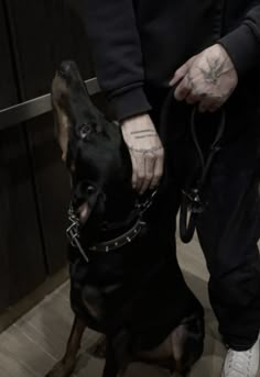 a black and white photo of a man holding his dog's leash while standing on the floor