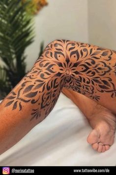 a person laying on top of a bed covered in black ink with an intricate design