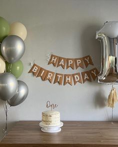 a birthday cake sitting on top of a wooden table next to balloons and streamers