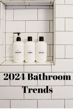 three white bottles sitting on top of a shelf in front of a tiled wall with the words, bathroom trend