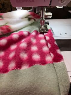 the sewing machine is working on the pink and white fabric that has been sewn