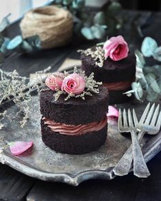 two pieces of chocolate cake on a plate with flowers and silverware next to it