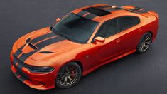 an orange dodge charger with black stripes on the hood is driving down a road