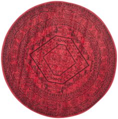 a round rug with an intricate design on the center and sides, in red tones