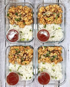 four glass containers filled with rice and meat covered in sauces on top of a wooden table