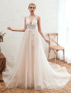 a woman in a wedding dress standing on a wooden floor with her hands out to the side