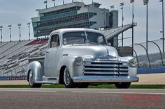 an old silver truck parked in front of a stadium