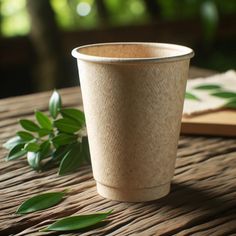 a paper cup sitting on top of a wooden table next to green leafy plants