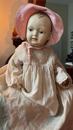 an old fashioned doll sitting on top of a bed