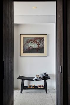 a painting hanging on the wall next to a bench with shoes on it and a pair of slippers