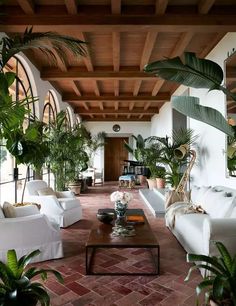 a living room filled with white couches and potted plants