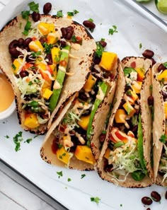 three tacos on a plate with salsa, beans and lettuce