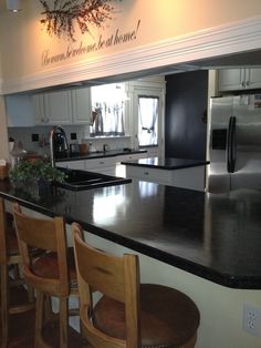 a kitchen with black counter tops and wooden chairs