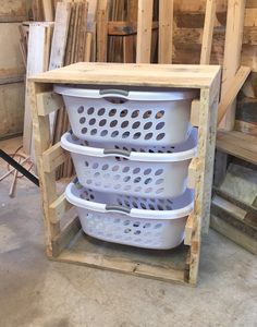 three white baskets stacked on top of each other in a storage area with wooden pallets