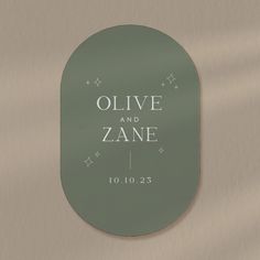 an oval glass sign with the words olive and zane written on it in white