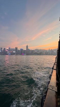 the sun is setting over the city skyline as seen from a boat on the water