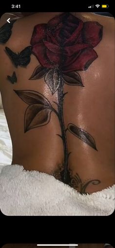 the back of a woman's body with tattoos on it and a red rose